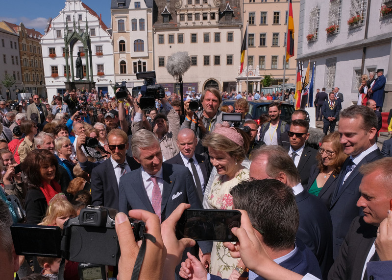 Das Foto zeigt das belgische Königspaar in einer Menschenmenge, die sich zur Begrüßung vor dem Alten Rathaus in Wittenberg versammelt hat.