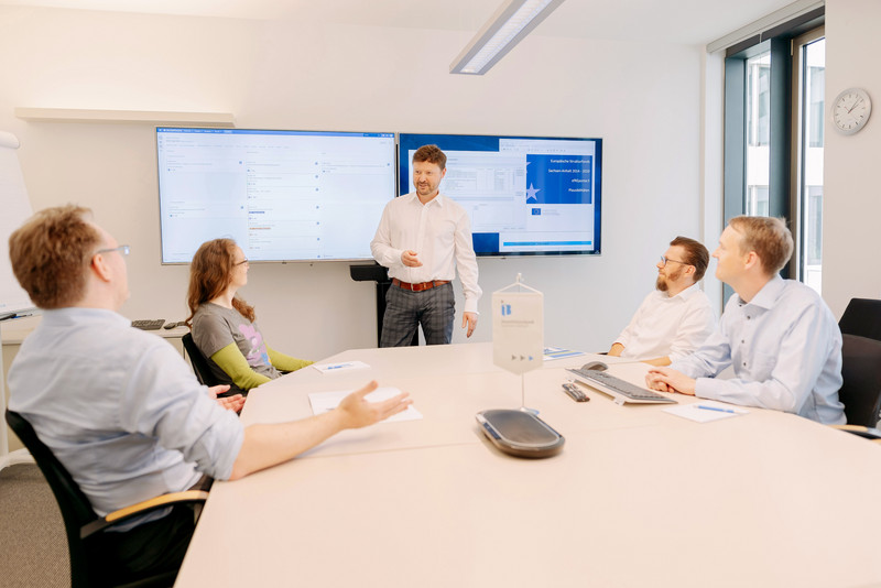Das Foto zeigt das Software-Entwicklerteam der Investitionsbank bei einer Besprechung. 