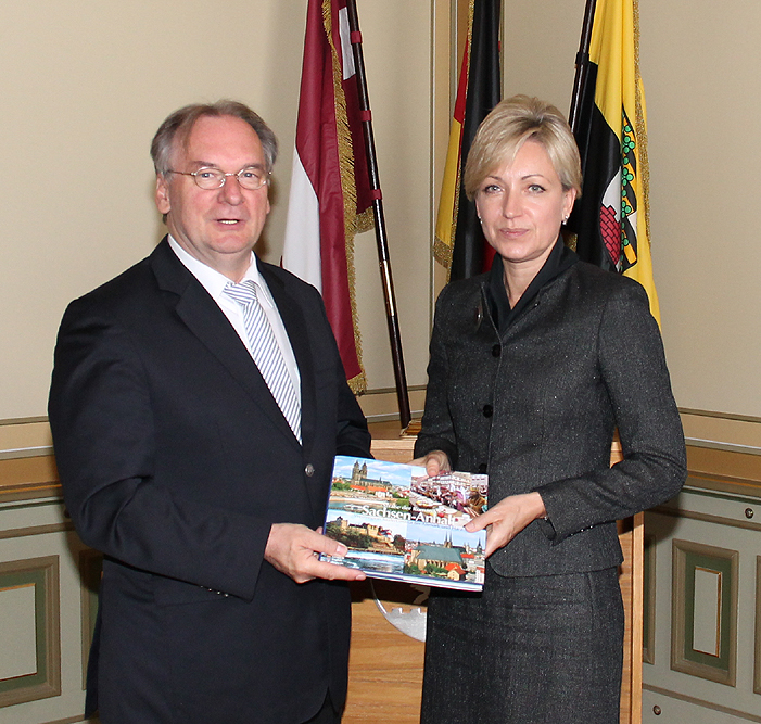 Foto: Staatskanzlei Sachsen-Anhalt/B. Rulf Das Foto zeigt Botschafterin Kuzma (rechts) und Ministerpräsident Haseloff vor den Flaggen Lettlands, der EU und Sachsen-Anhalts.