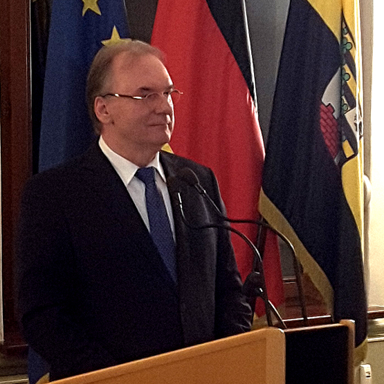 Das Bild zeigt Ministerpräsident Dr. Haseloff bei seiner Rede vor den Fahnen der EU, Deutschlands und Sachsen-Anhalts.