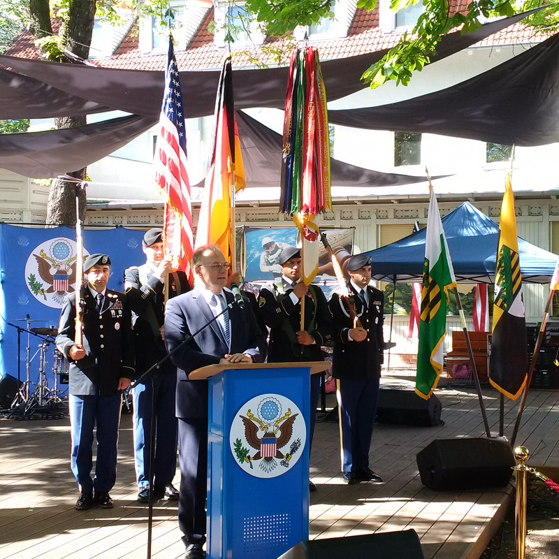 Das Bild zeigt Ministerpräsident Haseloff an einem blauen Rednerpult vor einer fünfköpfigen Fahnenabordnung der US-Armee. 