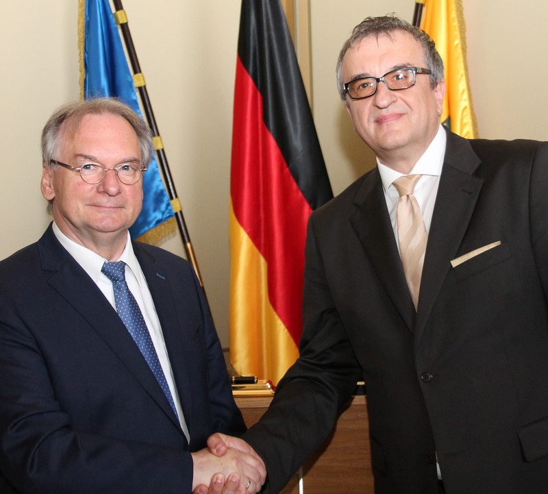 Das Foto zeigt links Ministerpräsident Haseloff und rechts Botschafter Źeljko Janjetović vor den Flaggen der EU, Deutschlands und Sachsen-Anhalts. 