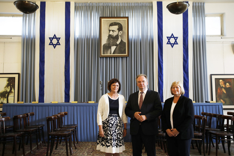 Das Foto zeigt von rechts Landtagspräsidentin Brakebusch, Ministerpräsident Haseloff und seine Gattin Gabriele in der Independence Hall in Tel Aviv, die mit einem großen Bild von Theodor Herzl und zwei israelischen Fahnen geschmückt ist.
