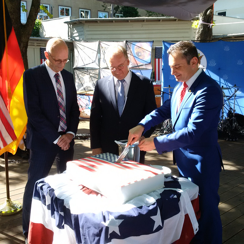 Das Bild zeigt von links Oberbürgermeister Wiegand und Ministerpräsident Haseloff, die Generalkonsul Eydelnant beim Anschneiden der Torte zuschauen.