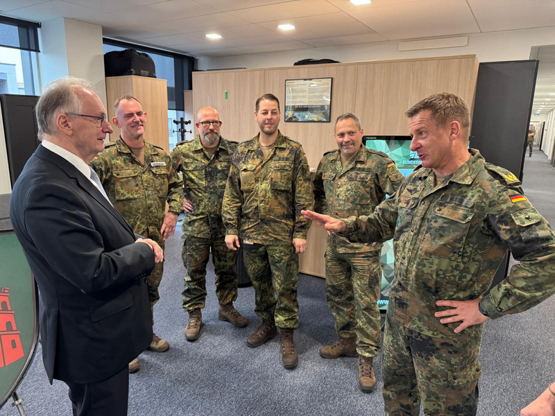 Links steht der Ministerpräsident und rechts eine Gruppe von fünf Männer in Bundeswehr-Uniformen.