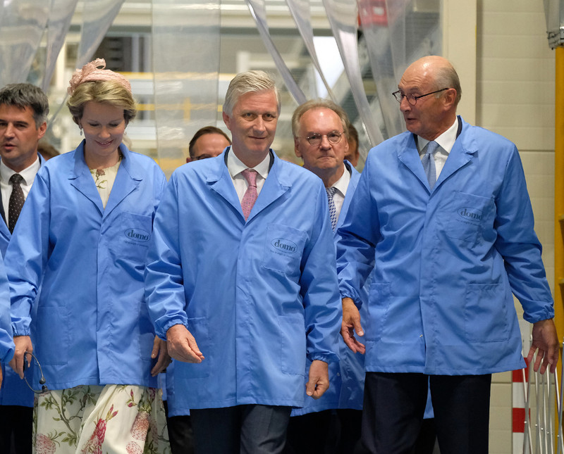Das Bild zeigt das Königspaar in hellblauen Kitteln beim Gang in eine Produktionshalle der DOMO Caproleuna GmbH.