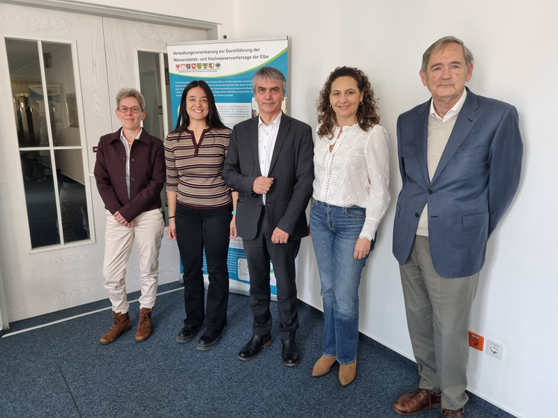 Gruppenbild mit fünf Personen vor einem Roll-Up und einer weißen Wand