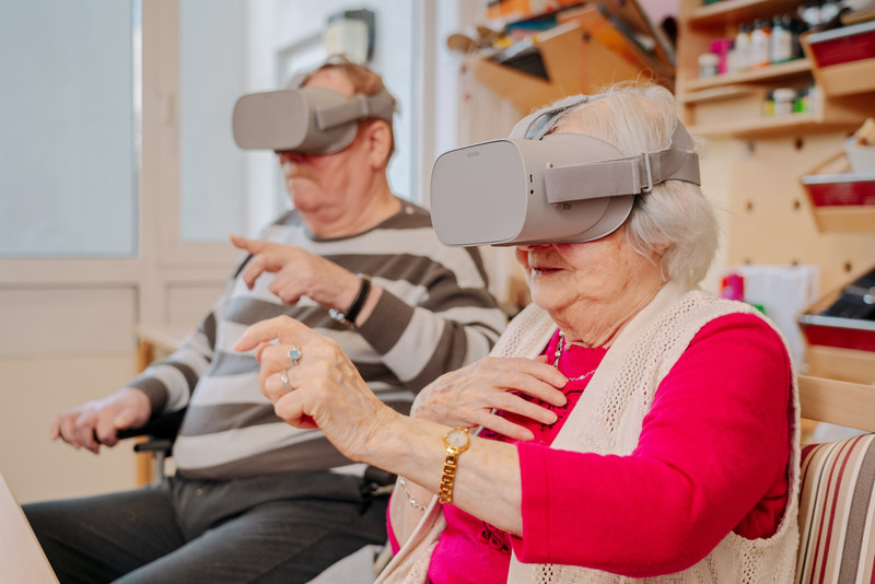 Das Bild zeigt einen älteren Herren und eine ältere Dame mit VR-Brille. 