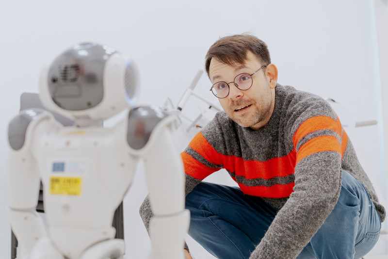 Das Foto zeigt einen Mann neben einem Roboter. 