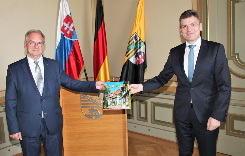 Das Foto zeigt links Ministerpräsident Reiner Haseloff und rechts Botschafter Marián Jakubócy vor den Flaggen der Slowakei, Deutschlands und Sachsen-Anhalts.
