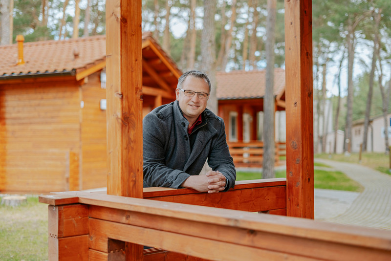 Das Bild zeigt Geschäftsführer Henrik Steek vor einem seiner neuen Ferienhäuser.