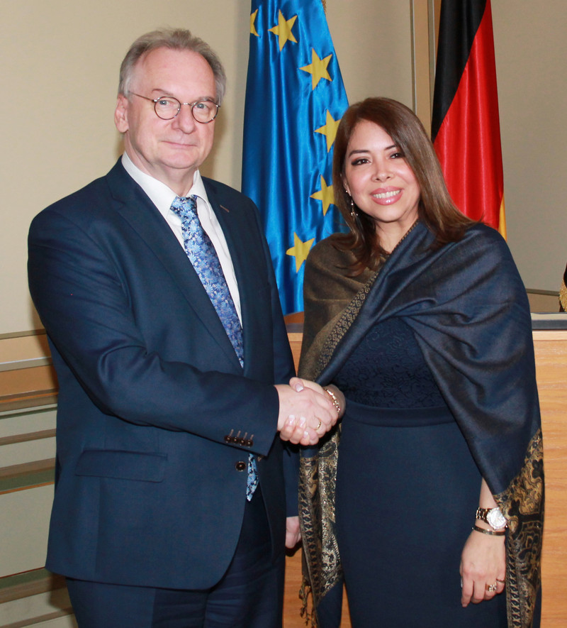 Das Bild zeigt links Ministerpräsident Haseloff und rechts Botschafterin Vilanova de von Oehsen vor den Flaggen der EU und Deutschlands.