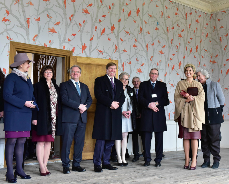 Das Bild zeigt neben weiteren Personen das Königspaar und das Ehepaar Haseloff sowie die Direktorin der Kulturstiftung Dessau-Wörlitz in einem Raum des Schlosses Oranienbaum, der mit einer Tapete mit Bäumen und Vögeln ausgestattet ist.