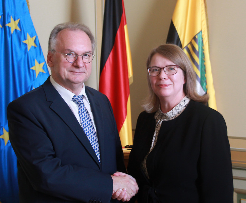 Das Foto zeigt links Ministerpräsident Haseloff und rechts Botschafterin Sipiläinen beim Handschlag vor den Fahnen der EU, Deutschlands und Sachsen-Anhalts.
