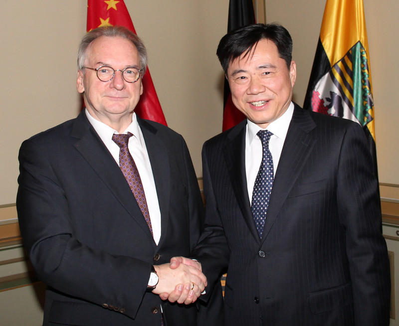 Das Bild zeigt links Ministerpräsident Haseloff und rechts Botschafter Wu beim Handschlag vor den Flaggen Chinas, Deutschlands und Sachsen-Anhalts.