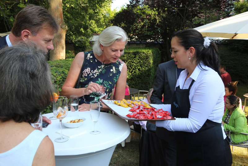 Eine Kellnerin serviert den Gästen im Garten Süßigkeiten