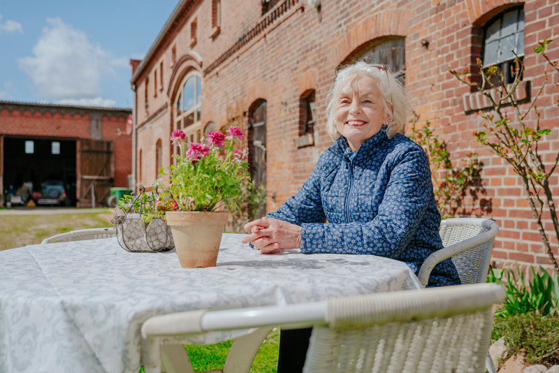 Das Bild zeigt Rita Spanner, die auf dem Havelhof Nitzow an einem Tisch sitzt.