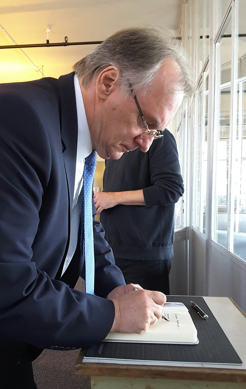 Das Bild zeigt Ministerpräsident Reiner Haseloff bei der Eintragung in das Gästebuch der Ausstellung "Simultanität der Moderne".