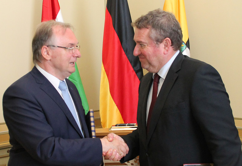 Das Foto zeigt links Ministerpräsident Haseloff und rechts Botschafter Györkös bei der Begrüßung vor den Flaggen Ungarns, Deutschlands und Sachsen-Anhalts.