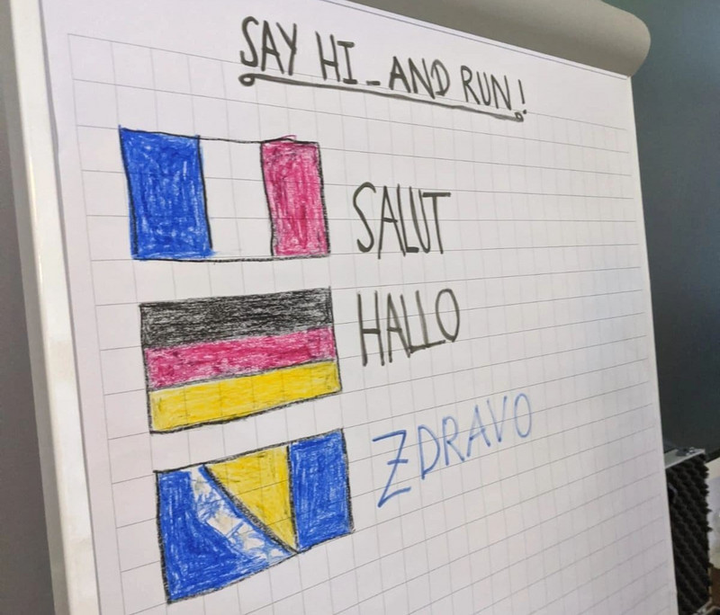 Auf einem Flipchart steht Hallo auf Deutsch, Französisch und Bosnisch geschrieben