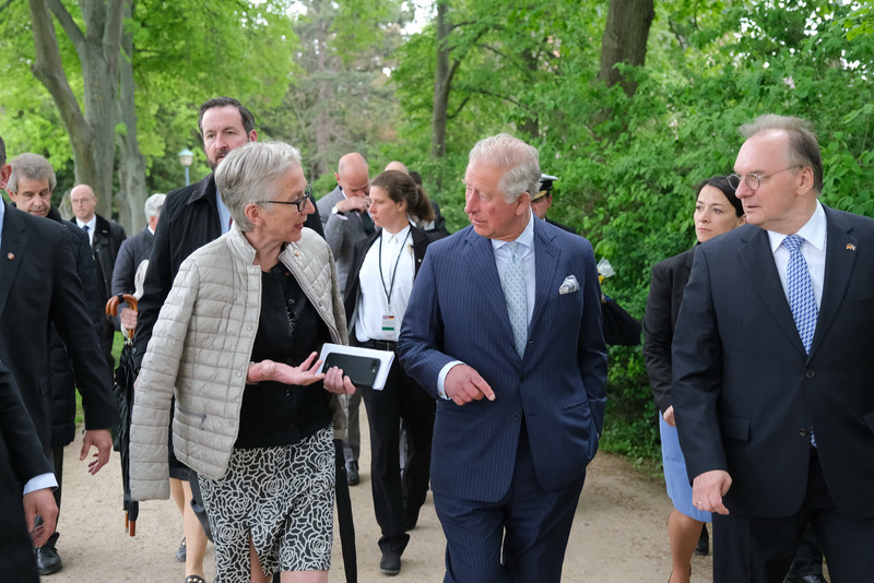 Das Bild zeigt neben weiteren Personen von links Direktorin Mang, Prinz Charles und Ministerpräsident Haseloff im Gespräch beim Gang durch die Parkanlage.