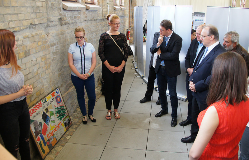 Das Foto zeigt rechts Ministerpräsident mt zwei Teilnehmerinnen des Eurocamps, die von ihrem Projekt der Handy-App für Rundgänge in Wittenberg berichten.