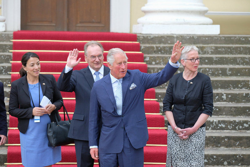 Das Bild zeigt in der Mitte Prinz Charles, der den Schaulustigen zuwinkt. Daneben sind Ministerpräsident Haseloff und die Direktorin der Kulturstiftung Dessau-Wörlitz, Mang, zu sehen.