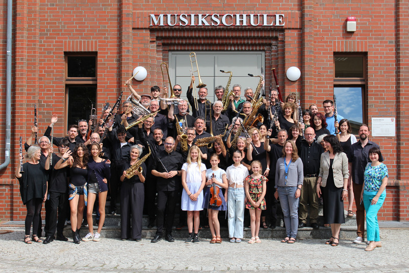 Eine Gruppesteht vor einem Gebäude Musikschule. 