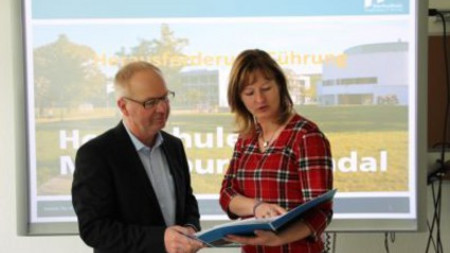 Das Bild zeigt Prof. Dr. Michael Hoffmann mit Frau Ilona Darius stehend. Frau Darius hält eine Infomappen in die beide Personen hineinschauen. (Bildquelle: Ministerium der Finanzen des Landes Sachsen-Anhalt)