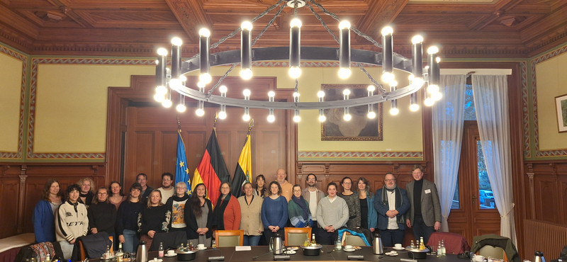 Eine Gruppe von etwa 25 Personen stehen hinter einem Tisch. 