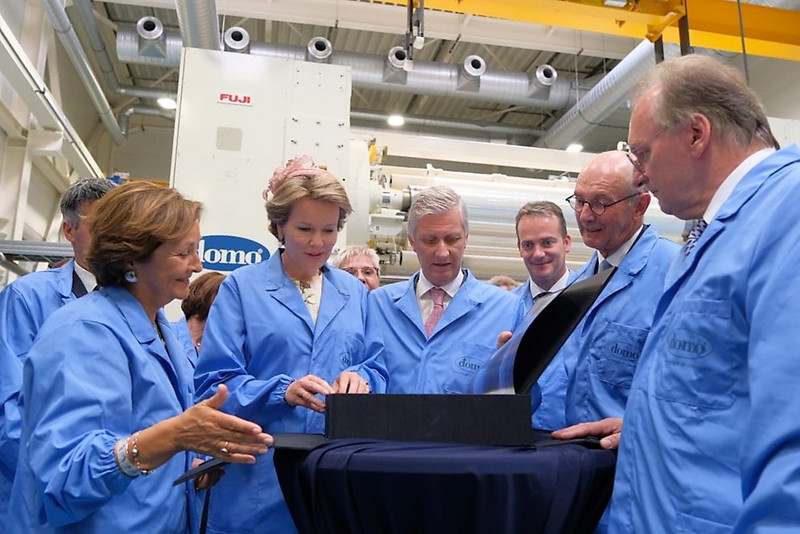 Das Bild zeigt unter anderem das Königspaar und den Ministerpräsidenten in hellblauen Kitteln in einer Produktionshalle der DOMO Caproleuna GmbH.