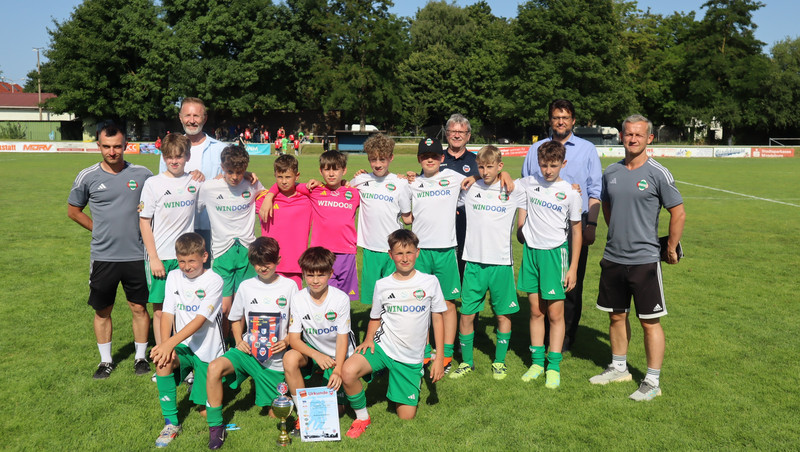 Mannschaftsbild auf dem Rasen. Sie tragen weißen Trikots und grünen Shorts. 