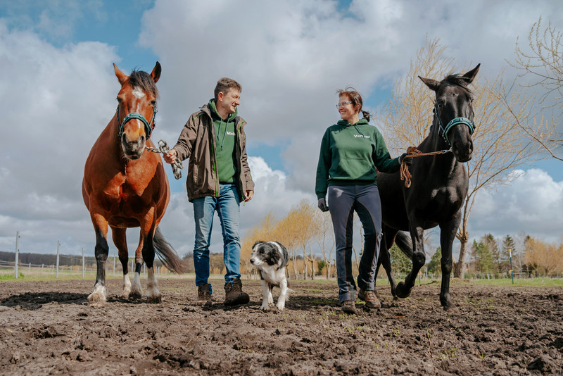 Das Bild zeigt Verena Elschner-Richter und ihren Mann mit zwei Pferden und ihrem Hund. 