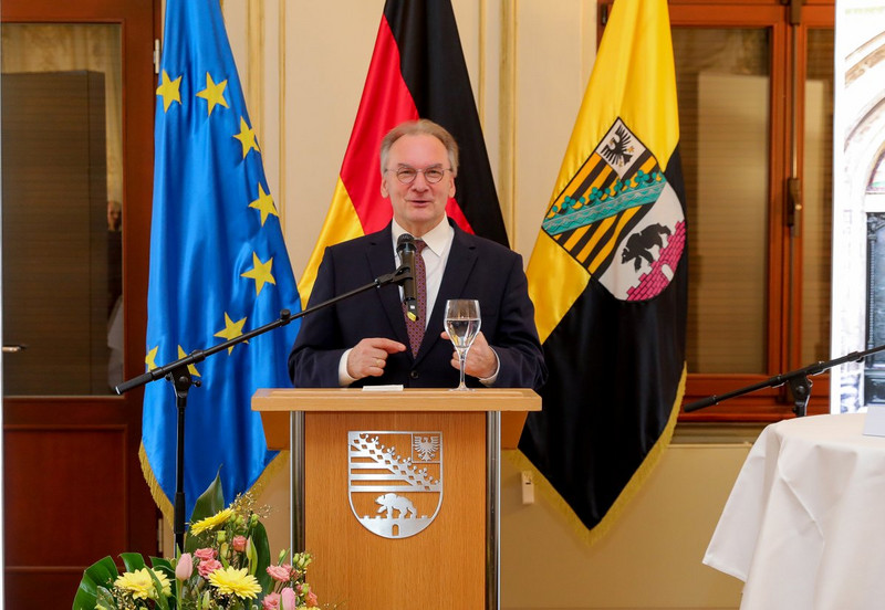 Das Bild zeigt Ministerpräsident Haseloff hinter einem Rednerpult und vor den Flaggen der EU, Deutschlands und Sachsen-Anhalts bei seiner Ansprache.