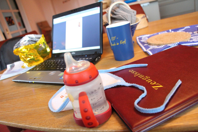 Schreibtisch mit Laptop, Lätzchen, Zeugnis und Nuckelflasche - Projekt MIKA
