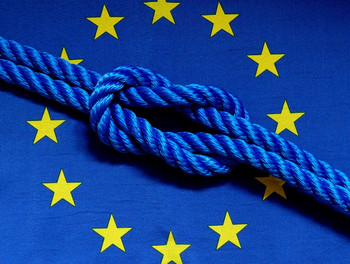 Das Bild zeigt die EU-Flagge mit einem Knoten darin. 