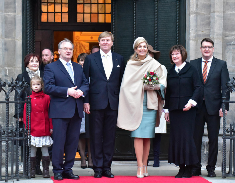 Das Bild zeigt König Willem-Alexander und Königin Máxima mit Ministerpräsident Haseloff, dessen Gattin und Wittenbergs Oberbürgermeister Zugehör auf dem Roten Teppich vor der geöffneten Thesentür der Schlosskirche.