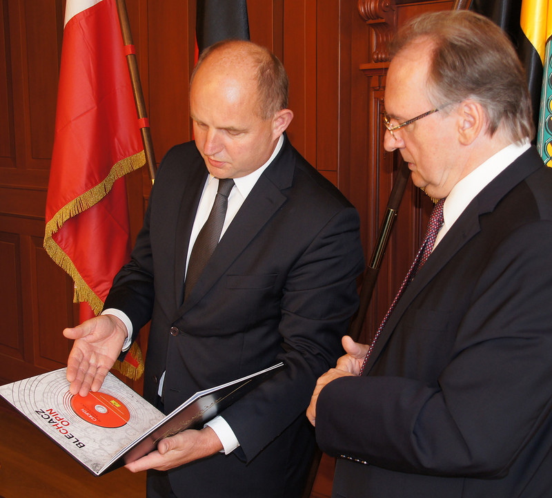 Das Foto zeigt links Marschall Całbecki, der als Gastgeschenk ein schmuckvolles großformatiges Buch mit einer CD mit Werken von Chopin an Ministerpräsident Haseloff überreicht. Im Hintergrund sind die Fahnen von Polen, Deutschland und Sachsen-Anhalt zu sehen.