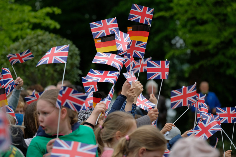 Das Bild zeigt mehrere britische und deutsche Fähnchen, die von Besuchern des Parks zur Begrüßung des Prinzen geschwenkt werden.