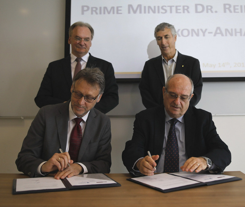 Das Bild zeigt die Chefs der Universität Magdeburg und des Technions Haifa an einem Tisch bei der Unterzeichnung der Kooperationsvereinbarung. Dahinter stehen Ministerpräsident Haseloff und der Vizepräsident des Technions, Professor Adam Schwartz.