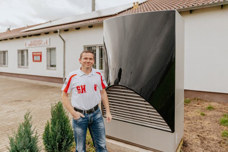 Das Bild zeigt den Vereinsvorsitzenden Stefan Horenburg neben der neuen Luft-Wärme-Pumpe. 
