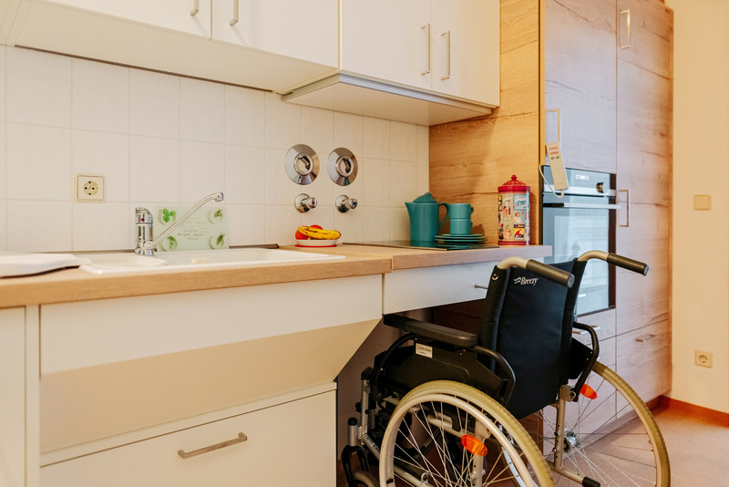 Das Bild zeigt einen Rollstuhl in einer beindertengerechten Küche. 