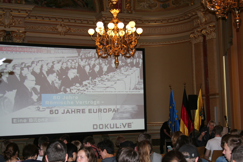 Das Foto zeigt eine Ausschnitt der Großbildleinwand und einen Teil des Publikums.