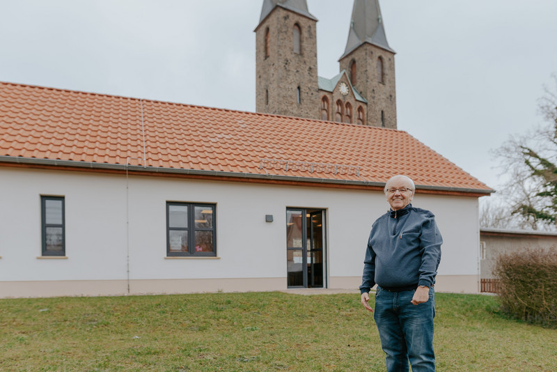 Das Bild zeigt den Bürgermeister von Westheide, Hans Hirche, vor dem neuen Dorfgemeinschaftshaus.
