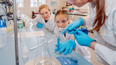 Das Foto zeigt Mädchen bei Experimenten in einem Labor. 