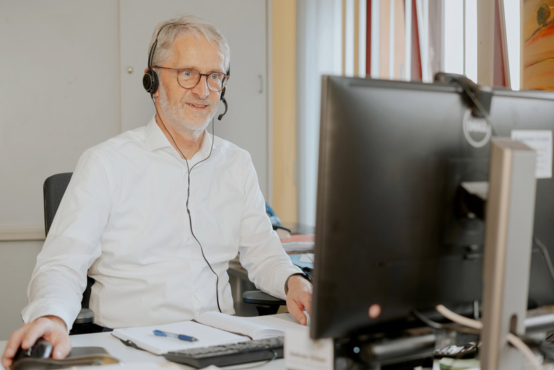 Das Foto zeigt Andreas Kröner mit einem Headset am PC. 