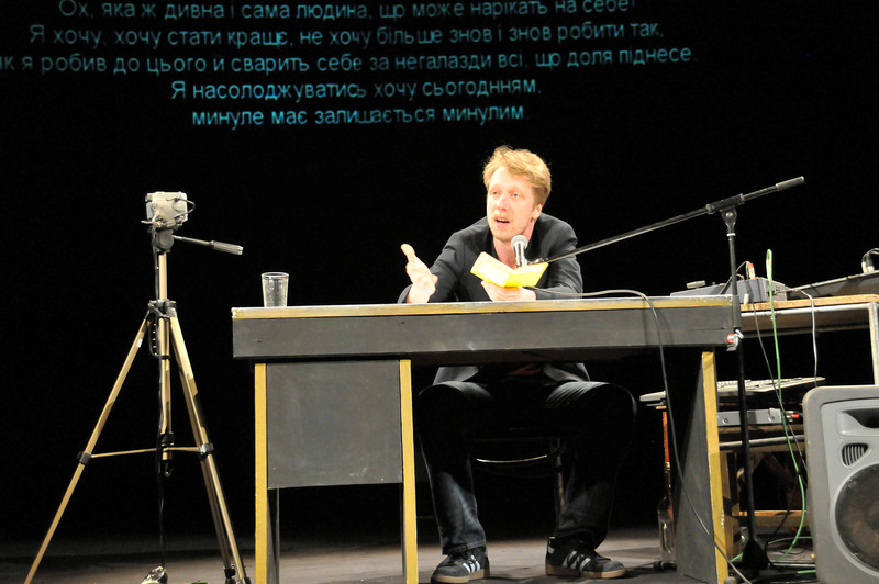 Das Bild zeigt den Schauspieler Raimund Widra vom Theater Magdeburg an einem Tisch auf der Bühne bei der Aufführung des Stückes "Werther" beim deutsch-ukrainischen Theaterfestival in Saporischschja.
